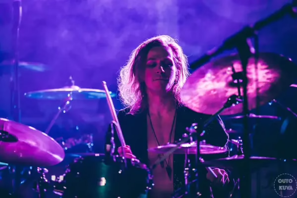 Live concert drumming in dramatic lighting.