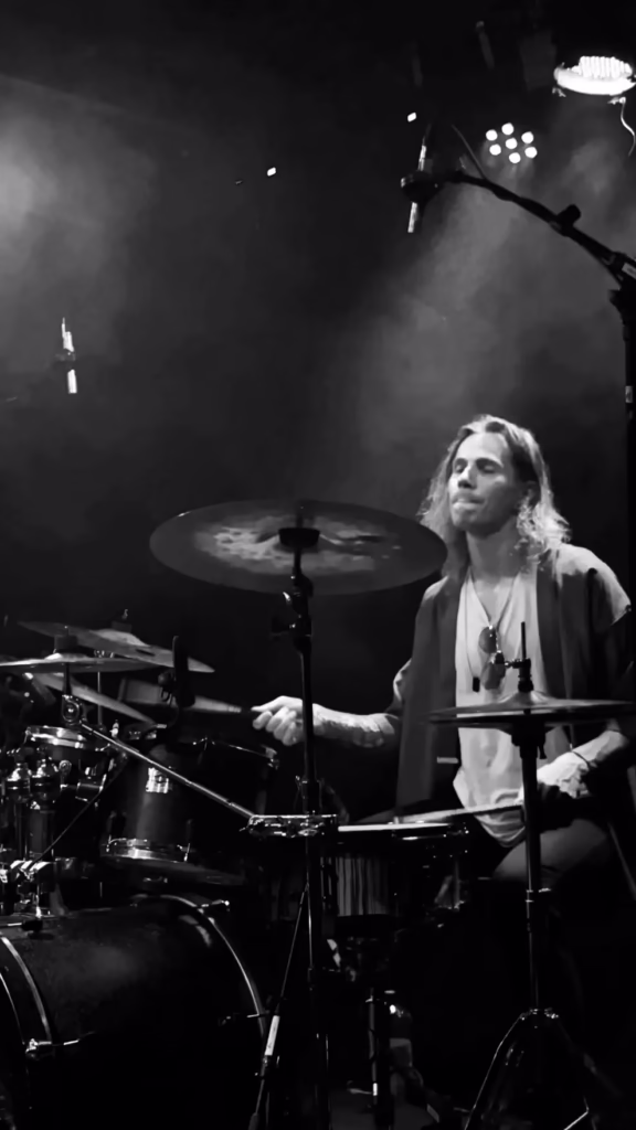 Jaro Väisänen, drummer performing on stage, dramatic lighting.